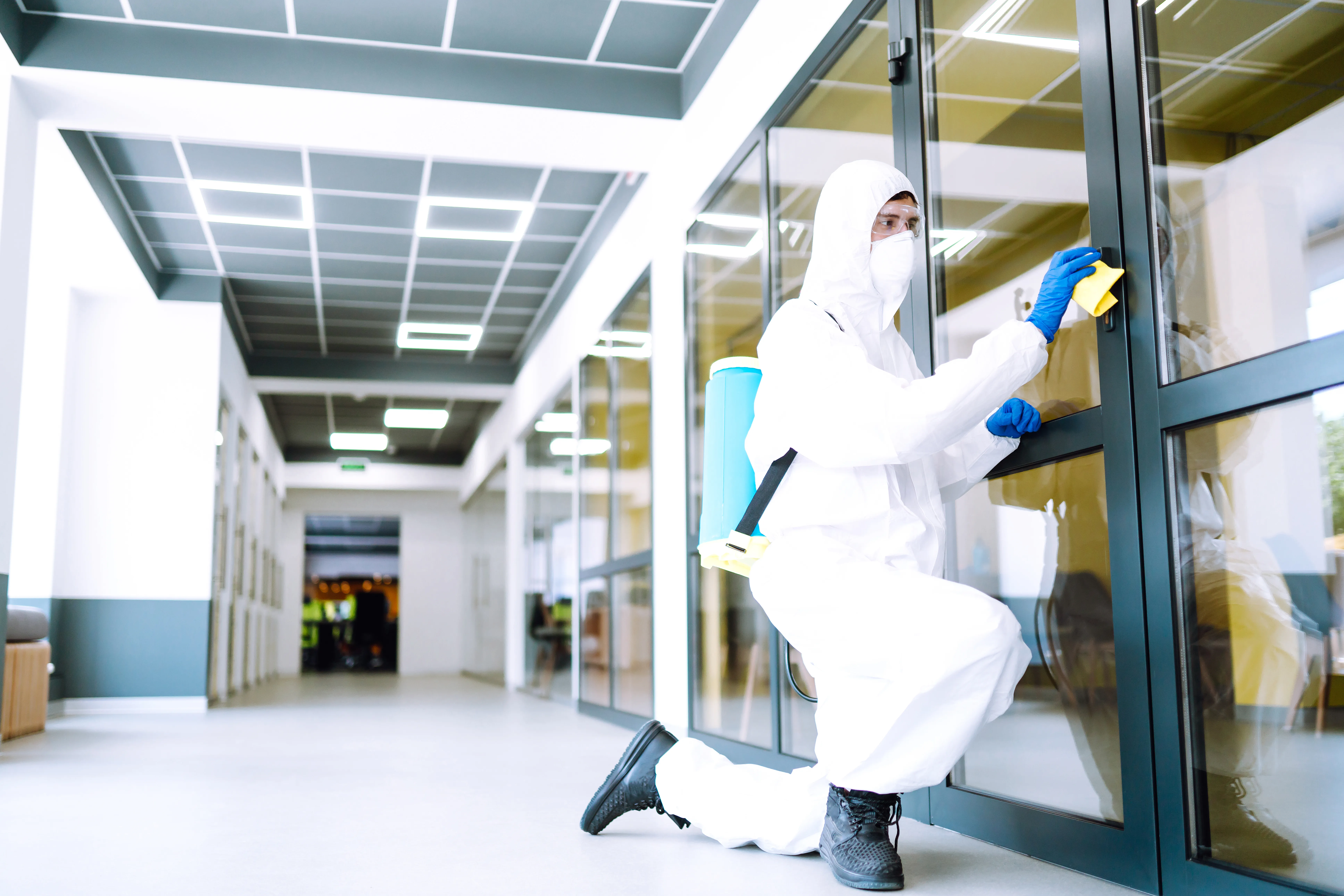 Persona de limpieza usando guantes limpiando un escritorio
